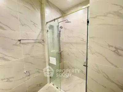 Luxurious modern bathroom with elegant marble tiles and glass shower enclosure.