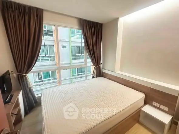 Cozy bedroom with large window and modern furnishings in a stylish apartment.