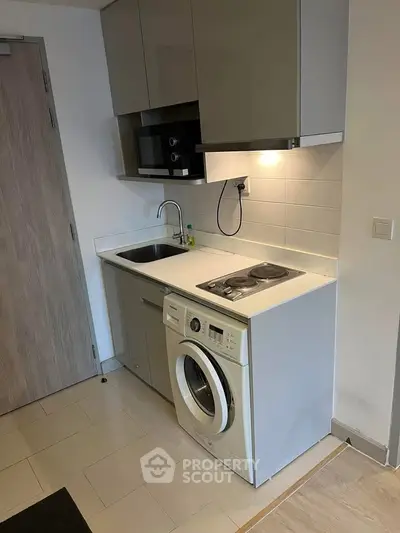 Compact kitchen with washing machine and modern appliances in a cozy apartment.