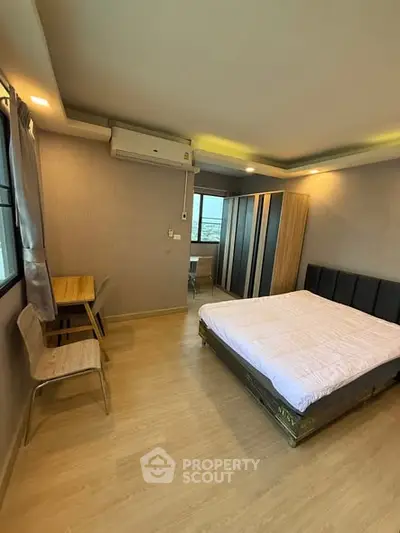 Spacious bedroom with modern decor and large window offering natural light.