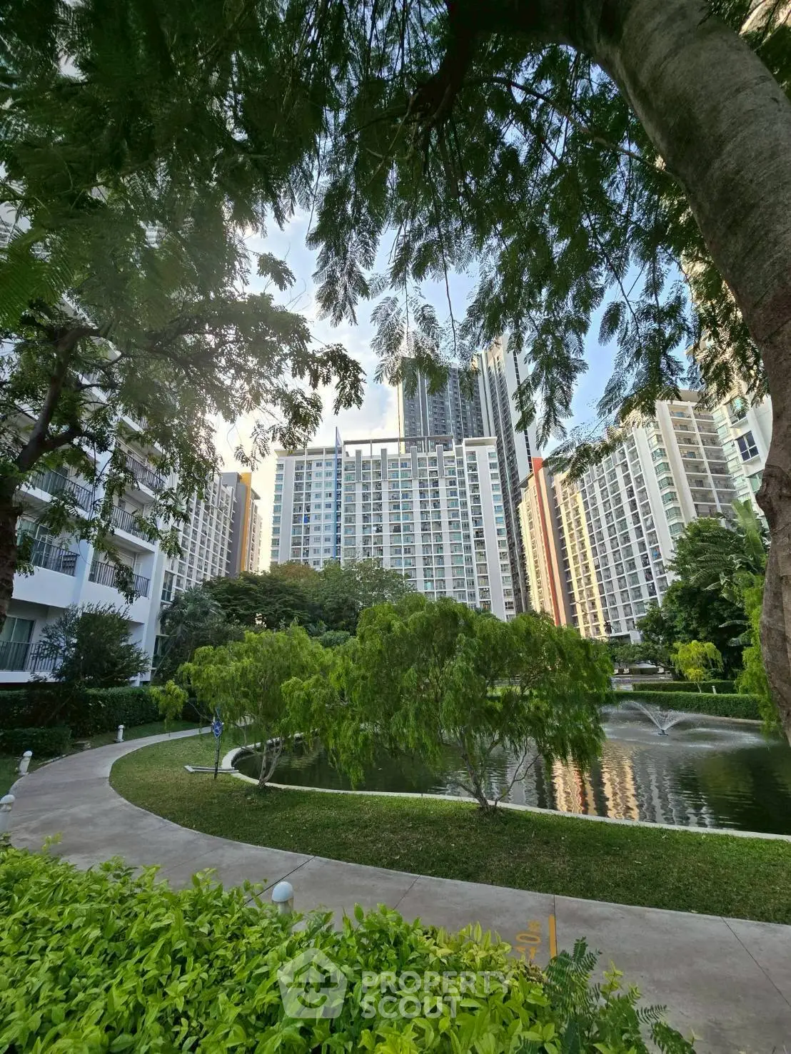 Stunning high-rise buildings with lush garden and serene pond view.