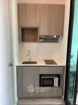 Compact modern kitchen with wooden cabinets and built-in microwave, ideal for small apartments.