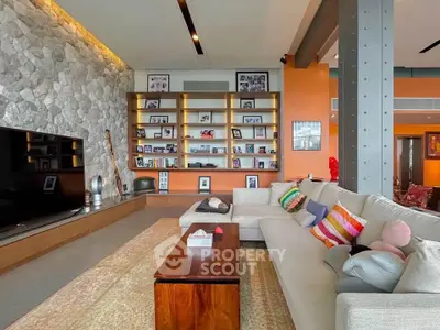 Spacious living room with modern decor and stone accent wall, featuring a large TV and cozy seating area.