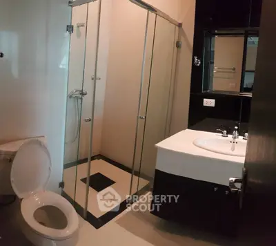 Modern bathroom with glass shower enclosure and sleek fixtures in a contemporary apartment.