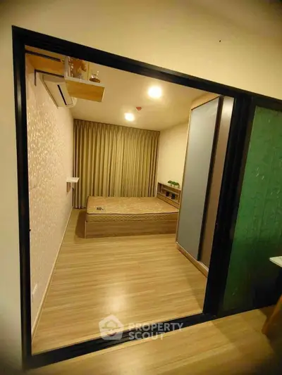 Modern bedroom with wooden flooring and sliding glass door, featuring a cozy bed and ambient lighting.
