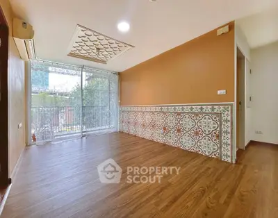 Spacious living room with unique patterned wall and large window overlooking greenery.