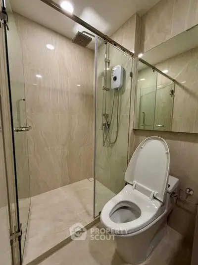 Modern bathroom with glass shower and sleek toilet in contemporary apartment.