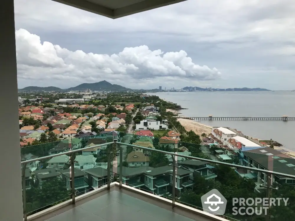 Stunning ocean view from high-rise balcony overlooking coastal town and lush greenery.