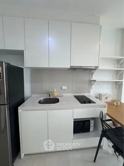 Modern kitchen with sleek white cabinetry, built-in appliances, and a compact dining area.