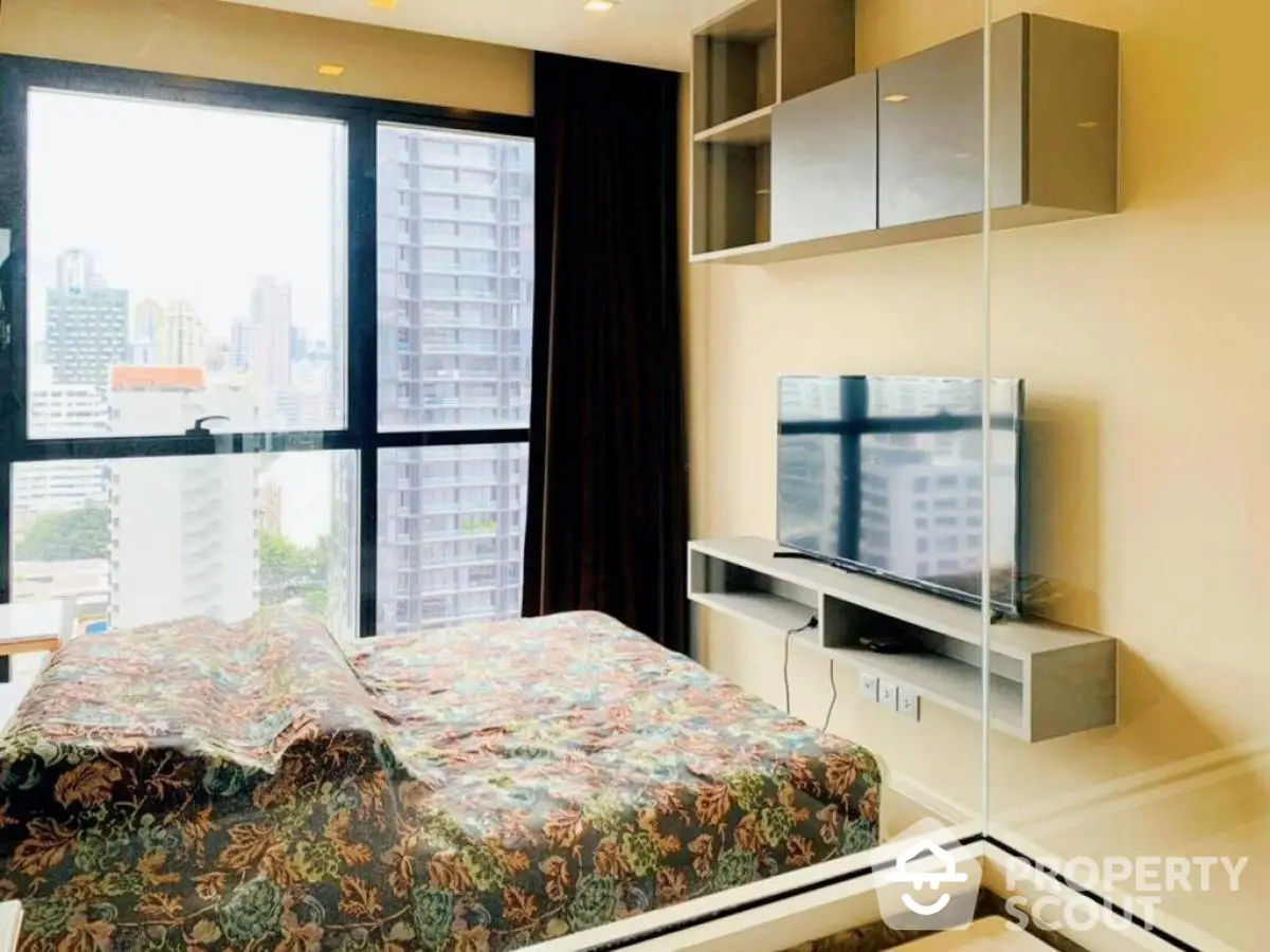 Modern bedroom with city view and mounted TV in high-rise apartment