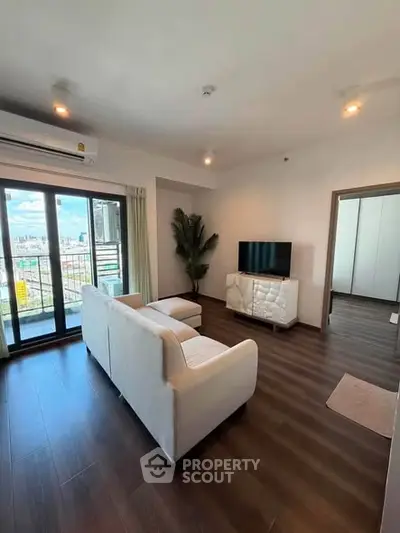 Modern living room with city view, featuring sleek furniture and large windows for natural light.