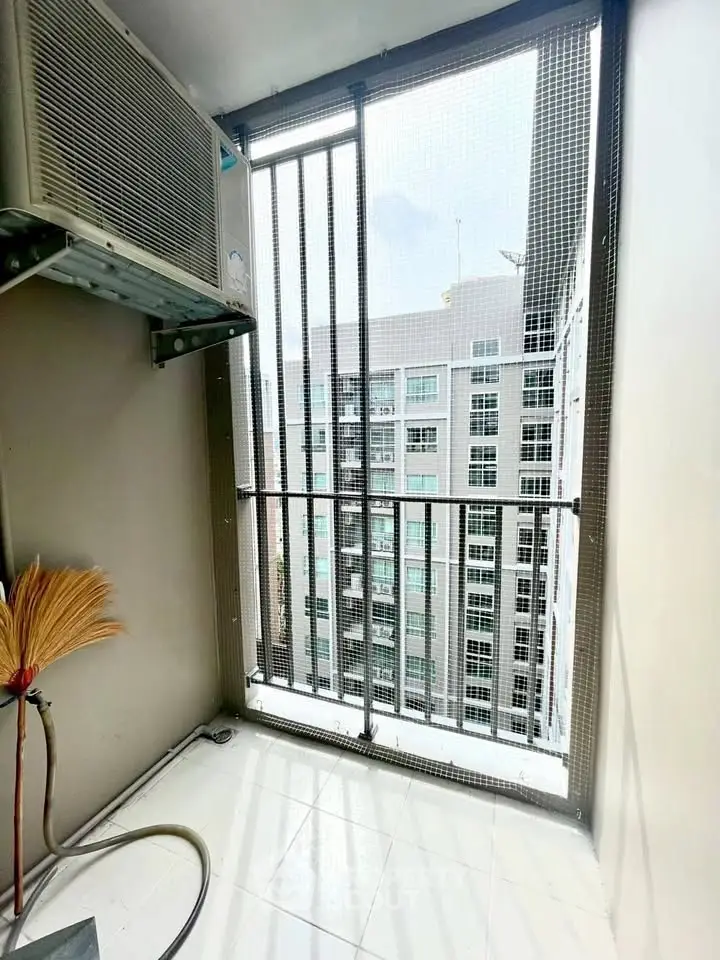 Compact balcony with city view and air conditioning unit in modern apartment.