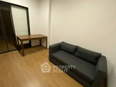 Modern living room with sleek black sofa and wooden table on polished floor.