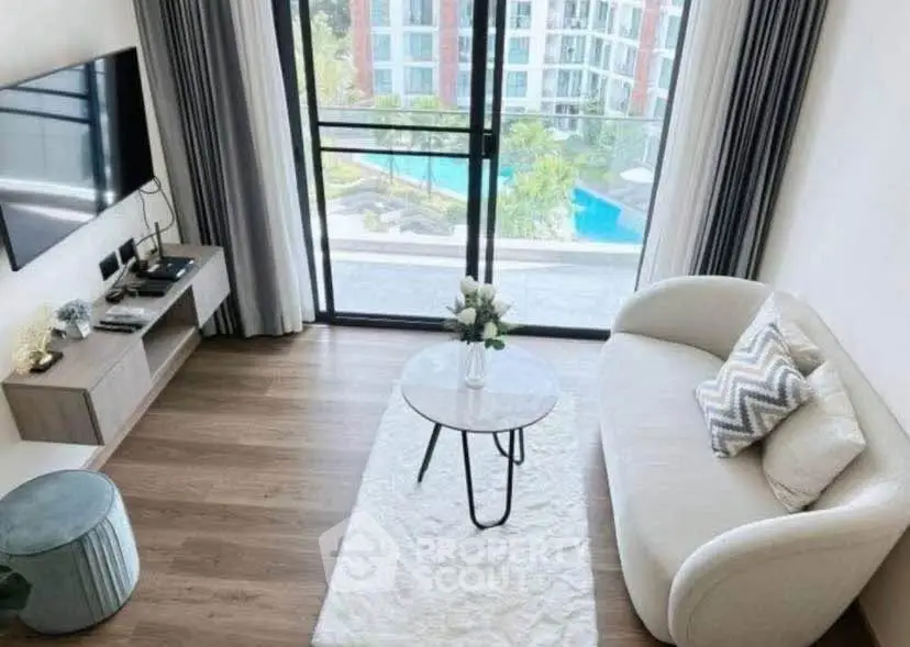 Modern living room with stylish decor and pool view, featuring a cozy sofa and sleek entertainment setup.