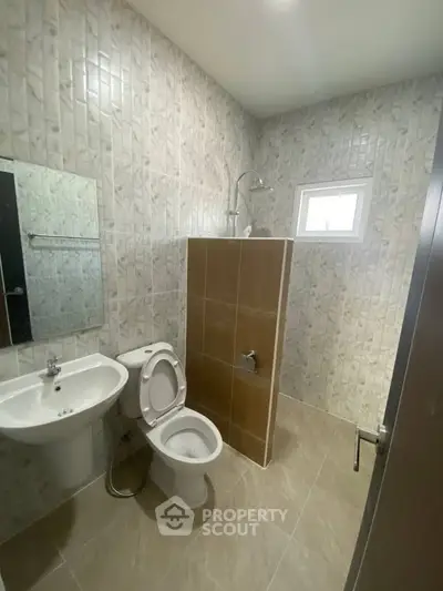 Modern bathroom with tiled walls, shower, and window for natural light.