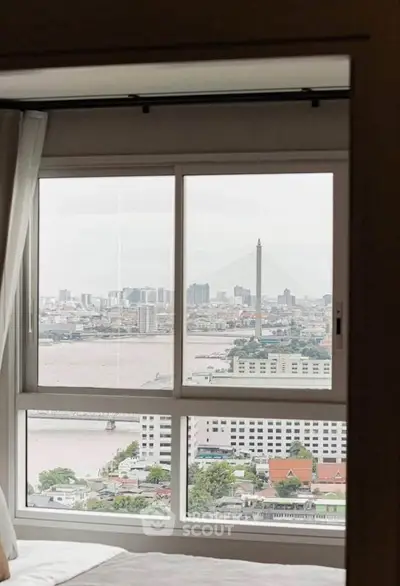 Stunning cityscape view from a high-rise apartment window overlooking a river and urban skyline.