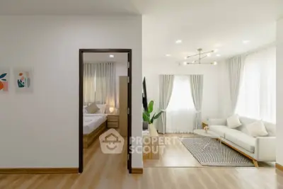 Modern open-plan living room with adjacent bedroom, featuring stylish decor and natural light.