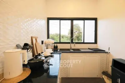 Modern kitchen with sleek black countertops and large window offering natural light.
