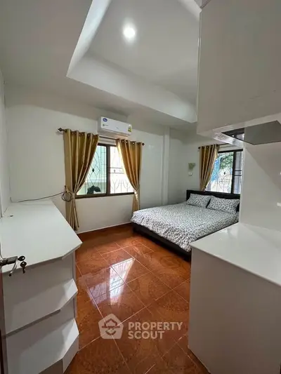Cozy bedroom with elegant curtains and polished tile flooring in a modern home.