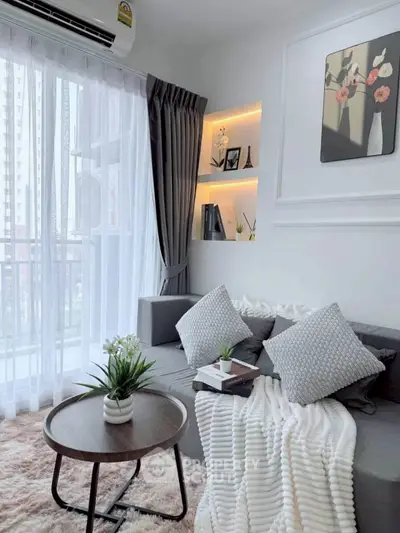 Chic modern living room with cozy sofa, stylish decor, and natural light from large window.