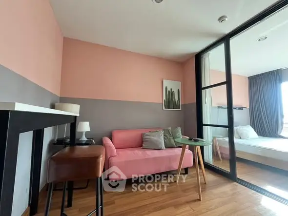 Chic modern living room with pink sofa and glass partition leading to cozy bedroom.