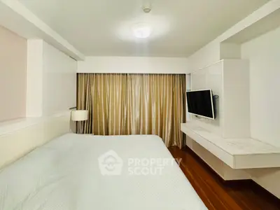 Spacious bedroom with modern decor and wall-mounted TV in a stylish apartment.