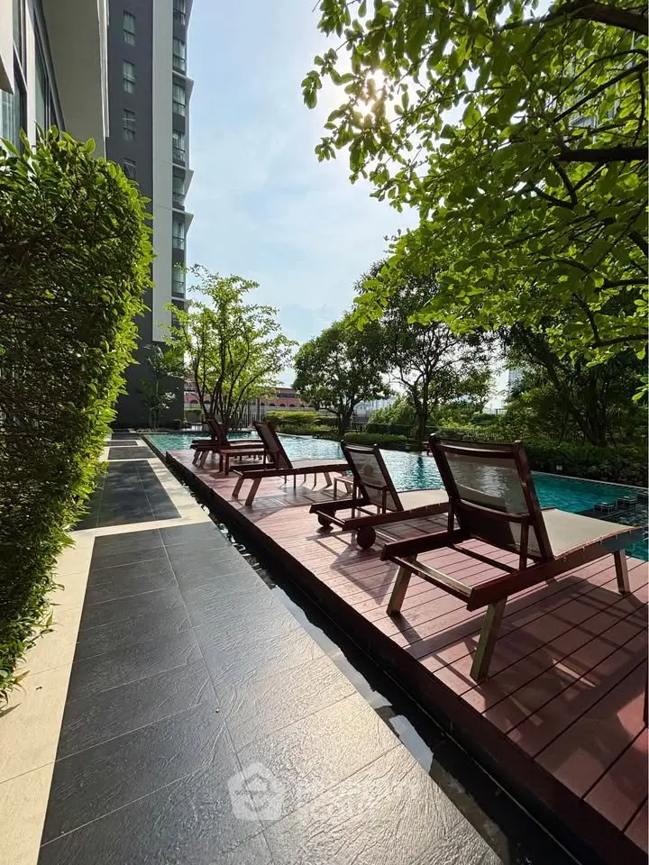 Luxurious poolside area with sun loungers and lush greenery in a modern residential complex.