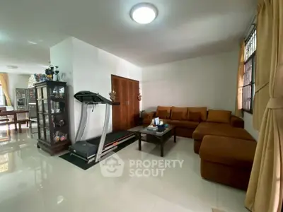 Spacious living room with modern treadmill and cozy sectional sofa in a well-lit home.