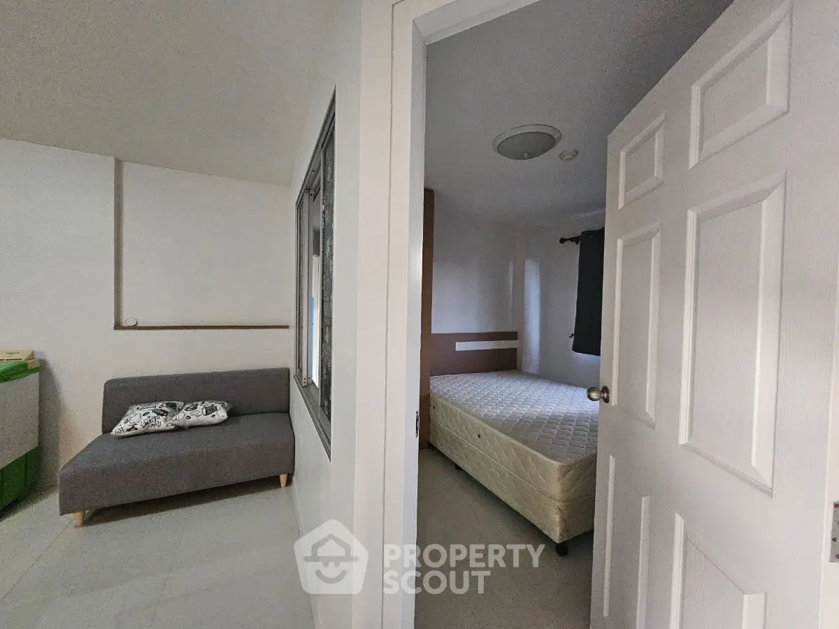 Cozy bedroom with adjacent living area, featuring a comfortable sofa and a neatly made bed, perfect for modern living.