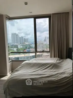 Spacious bedroom with large window offering stunning city views in modern apartment.