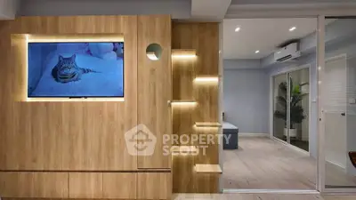 Modern living room with wooden paneling and built-in TV, featuring sleek lighting and sliding glass doors.