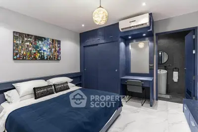 Modern bedroom with blue accents, stylish artwork, and ensuite bathroom in luxury apartment.