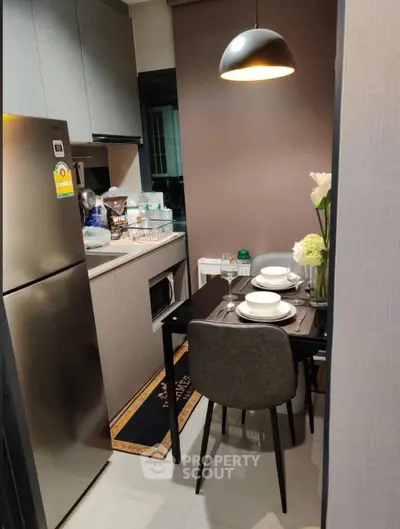 Cozy modern kitchen with dining area, featuring sleek appliances and elegant lighting.