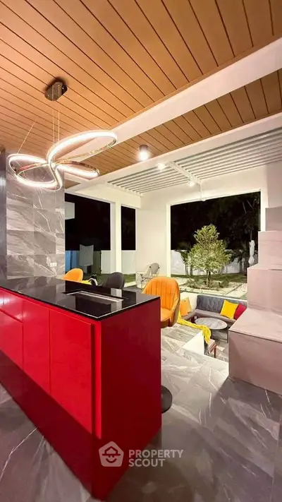 Modern living room with vibrant red kitchen island and stylish lighting