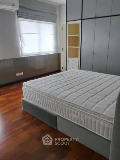 Spacious bedroom with elegant wooden flooring and large wardrobe