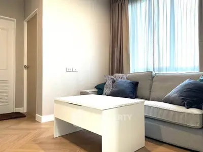 Modern living room with cozy sofa and stylish coffee table, featuring elegant curtains and wooden flooring.