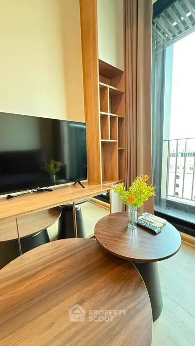 Modern living room with stylish wooden furniture and large TV, featuring a cozy balcony view.