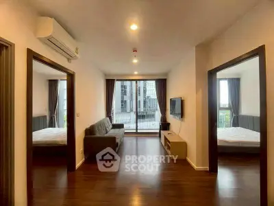 Spacious modern living room with wooden flooring and large windows in a stylish apartment.