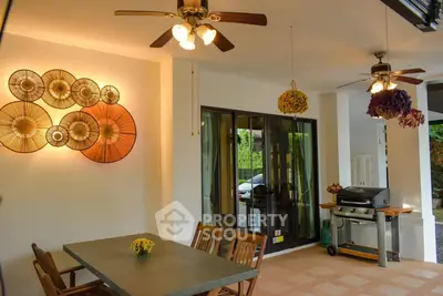 Charming outdoor dining area with ceiling fans and decorative wall art, perfect for entertaining.