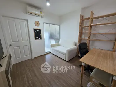 Cozy study room with wooden flooring, white sofa, desk, and shelving unit.