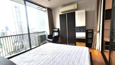 Modern bedroom with city view and balcony access in high-rise apartment