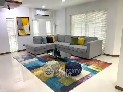 Spacious living room with modern sectional sofa and colorful rug, perfect for relaxation and entertaining.