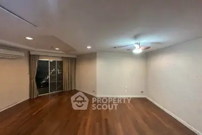 Spacious empty living room with wooden flooring and ceiling fan, ideal for customization.