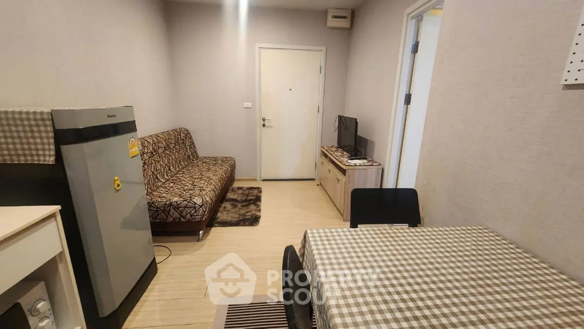 Cozy living room with patterned sofa, dining table, and compact kitchen area in modern apartment.