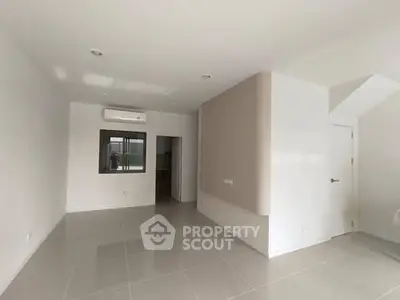 Spacious empty living room with modern tile flooring and neutral walls.