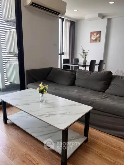 Modern living room with sleek furniture and dining area, featuring a stylish marble coffee table and cozy ambiance.
