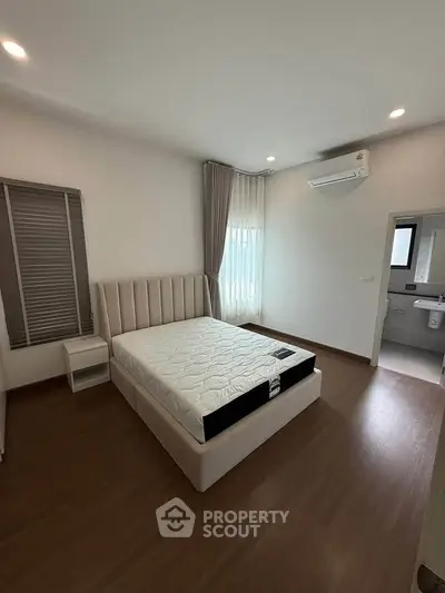 Spacious bedroom with modern design, featuring a large bed and natural light from windows.