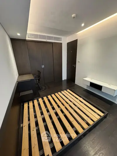 Modern bedroom with dark wood flooring and built-in wardrobe