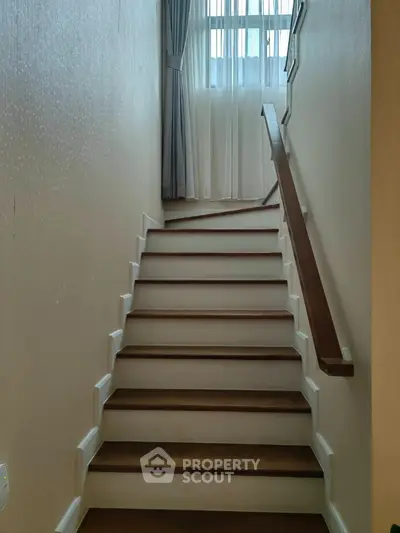 Elegant staircase with wooden handrail and natural light from window