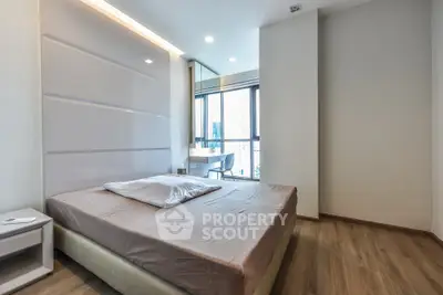 Modern bedroom with large window and wooden flooring in a stylish apartment